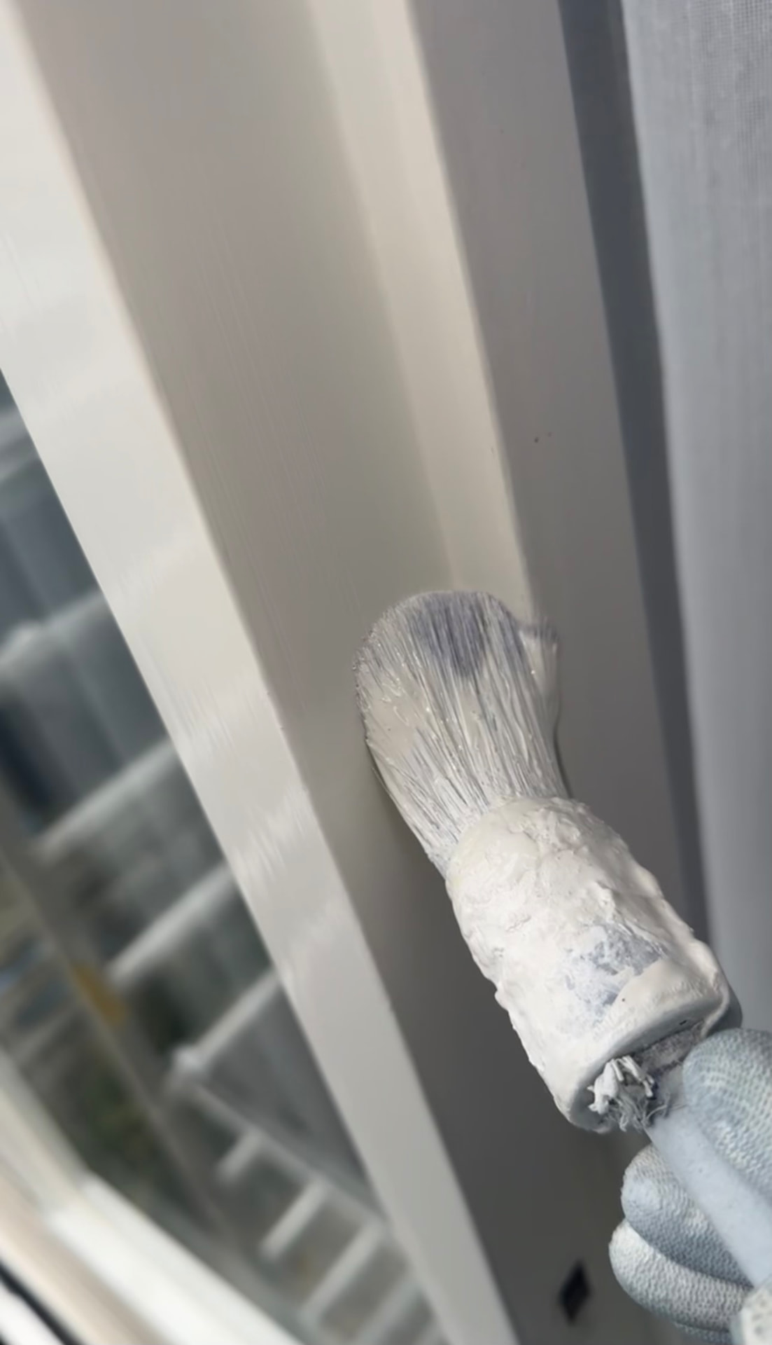 Kwast werkt een kozijn bij tijdens schilderwerk binnen